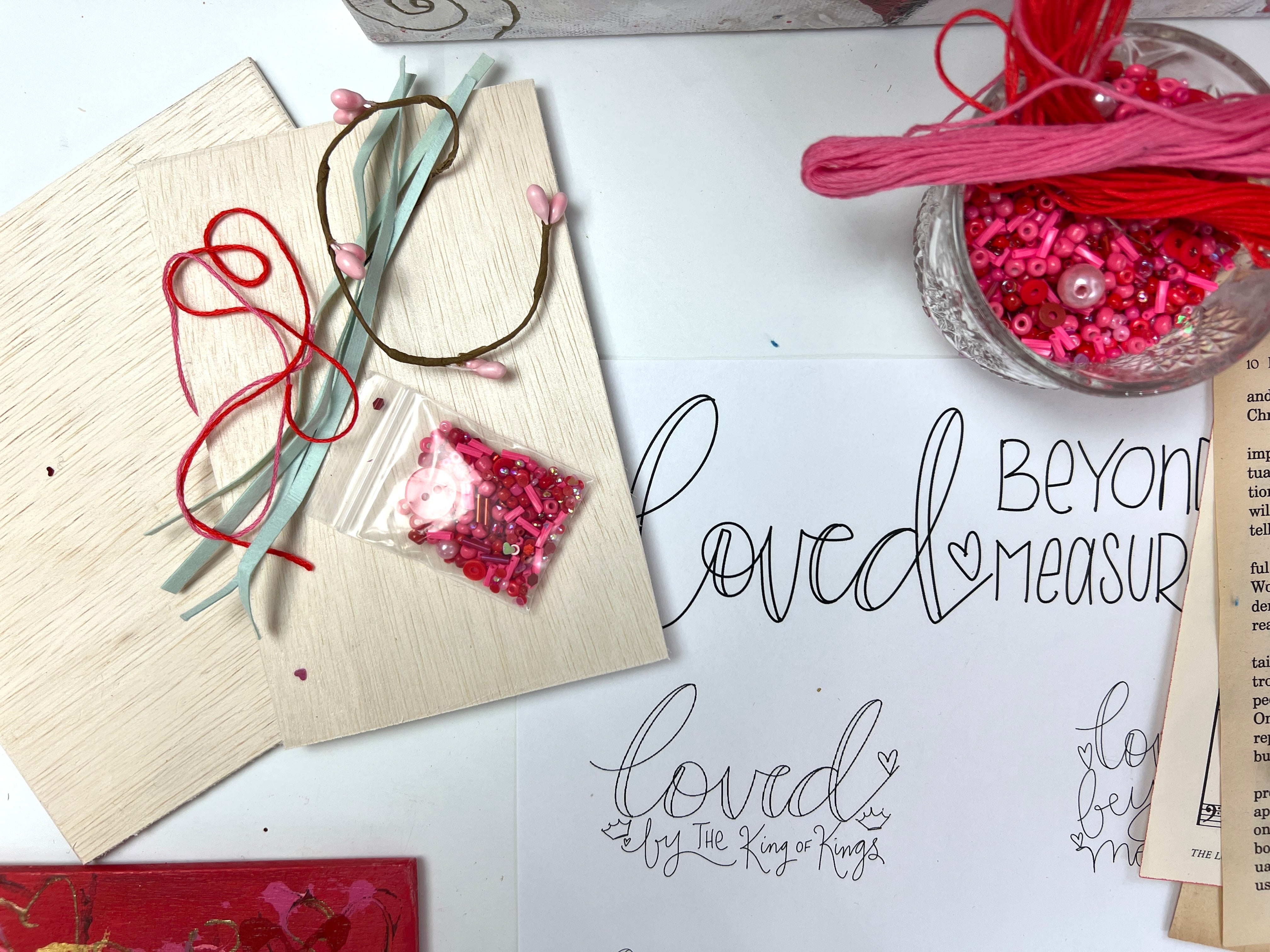 Crafting materials and decorative elements on a table with 'Loved Beyond Measure' traceable.